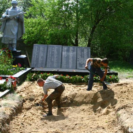 Поисковики засыпают могилу